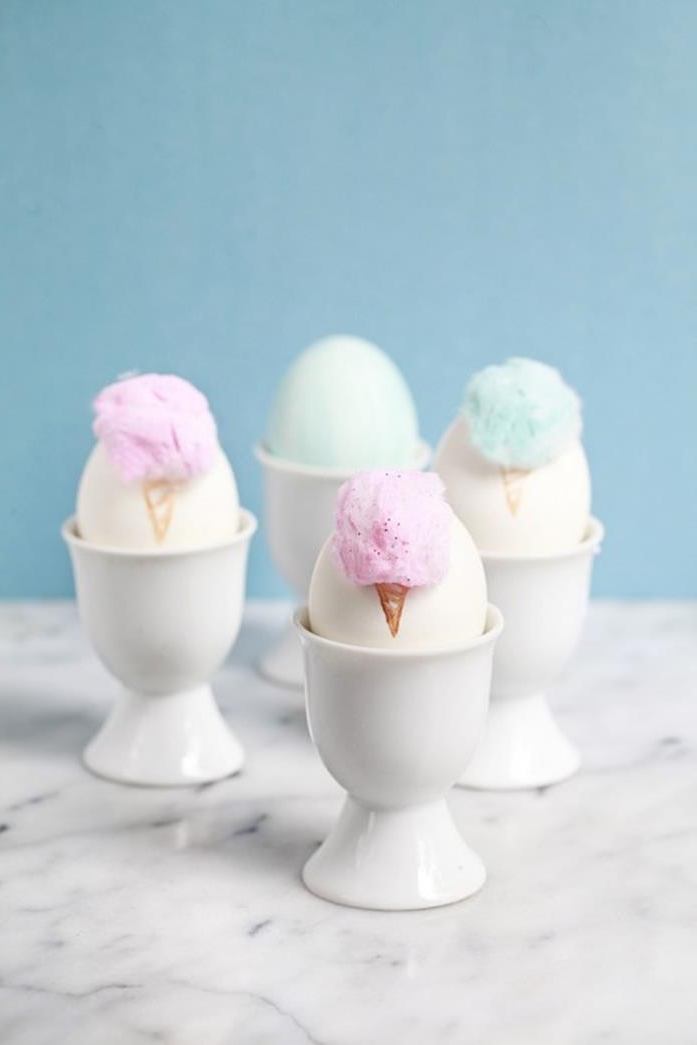 white ceramic egg dishes, containing plain white eggs, decorated with pale pastel blue and pink pieces of cotton, looking like cotton candy, easter egg designs, marble surface
