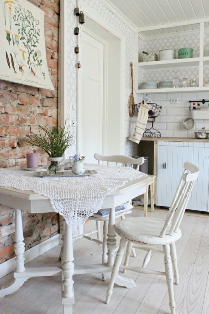 rough brick wall, inside a industrial shabby chic kitchen, white antique table with peeling paint, and matching chairs, various vintage kitchen furniture pieces