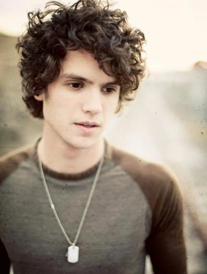very dark brown curly hair, with side part, guys haircuts, on black-eyed teenager in grey and brown top, wearing dog tags