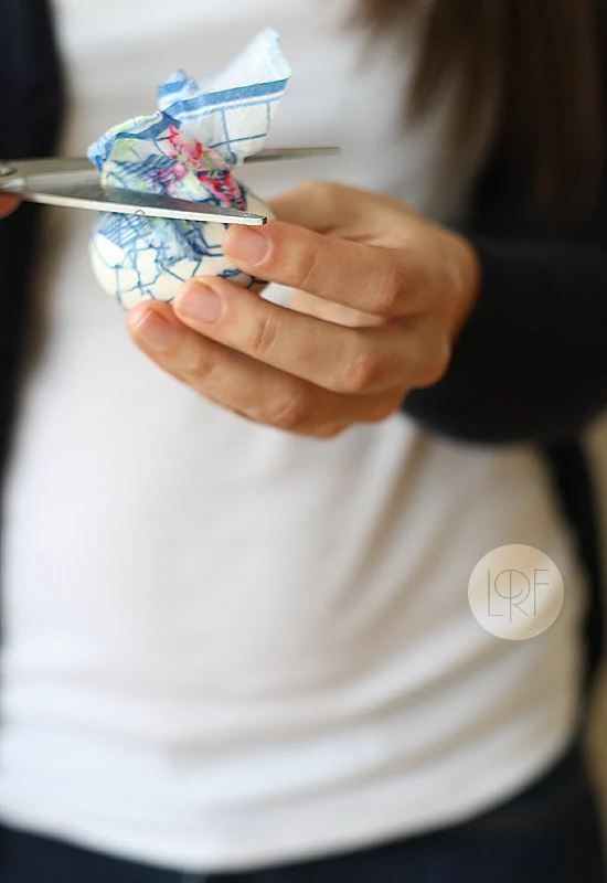 egg wrapped in a paper napkin, woman using scissors, to cut excess napkin, easter egg decorating 