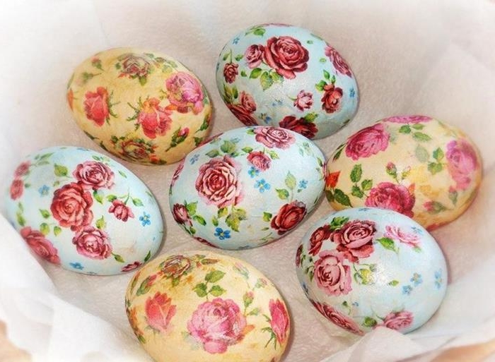 rose patterned easter eggs, in pale blue and pale yellow, made with decoupage techniques, placed on a white napkin