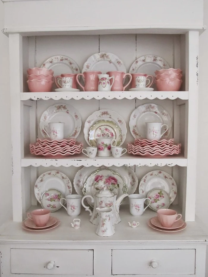 plates and cups in pastel pink, and in white with floral motifs, with matching jugs and teapots, country chic décor, white shabby wooden cupboard