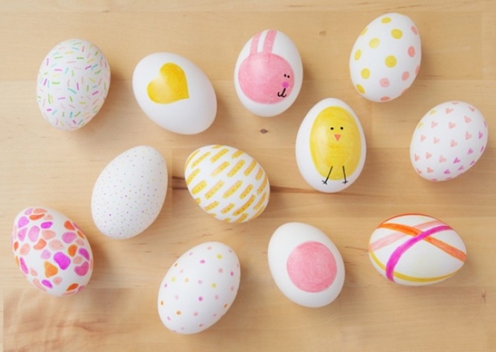 twelve white eggs, decorated with drawings of a chick and bunny, hearts and dots, lines and spots, all in pink orange and yellow, easter egg ideas 