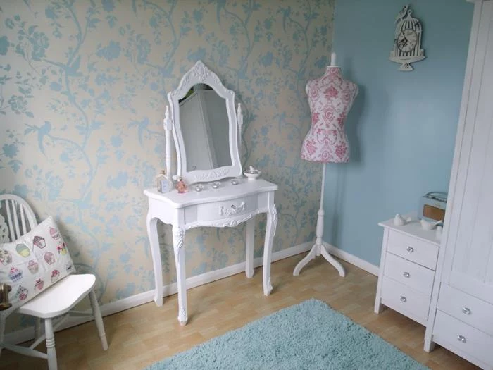 dressmaker's dummy in white and pink, near an ornamental, french antique dresser, shabby chic decorating, cream and pale blue wallpaper, white wardrobe and cupboard