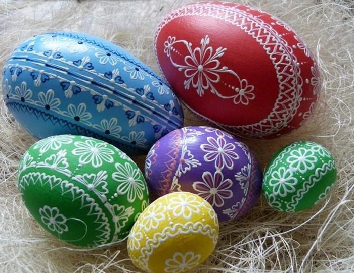 traditional eastern european easter eggs, different sizes dyed in red, blue and green, yellow and purple, and decorated with complex, white floral patterns