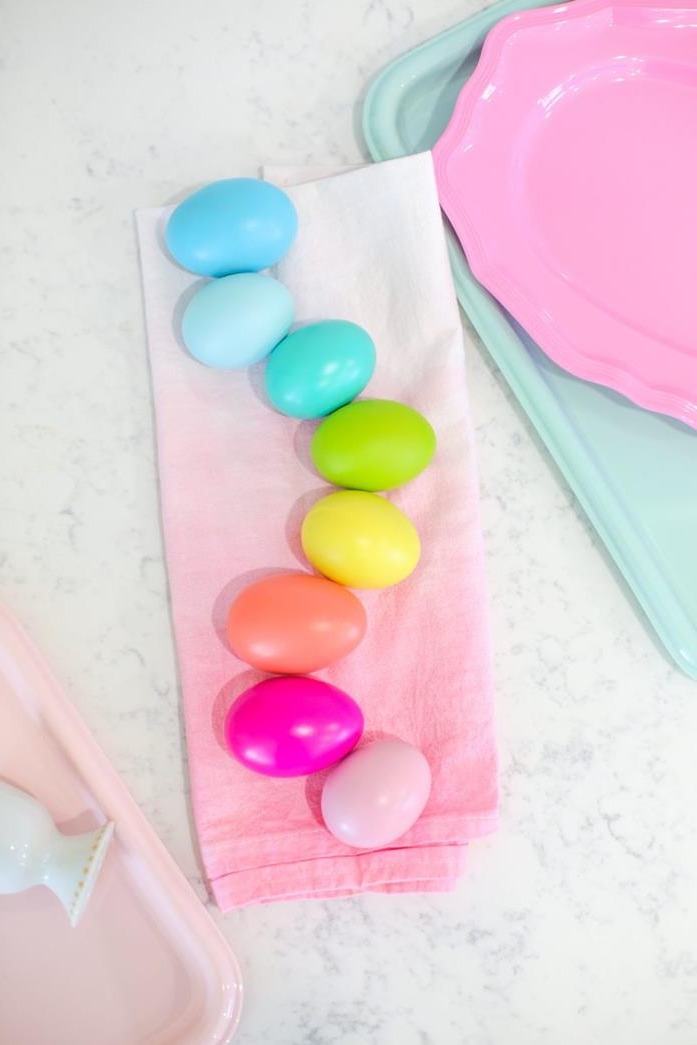 rainbow made from eggs dyed in different colors, easter egg ideas, light and dark blue, orange and yellow, green and blue, placed on a pale pink napkin