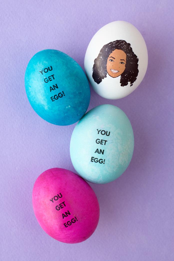 close up of an easter egg with a cartoon drawing of oprah winfrey, placed next two blue eggs, and one pink egg, all bearing the words you get an egg
