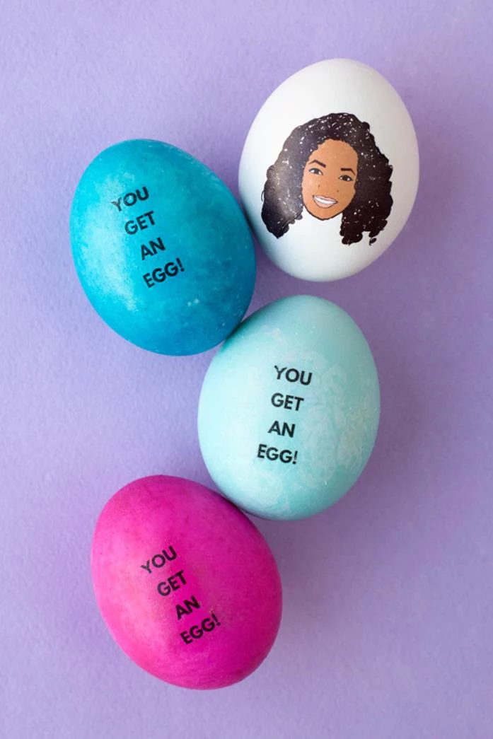 close up of an easter egg with a cartoon drawing of oprah winfrey, placed next two blue eggs, and one pink egg, all bearing the words you get an egg