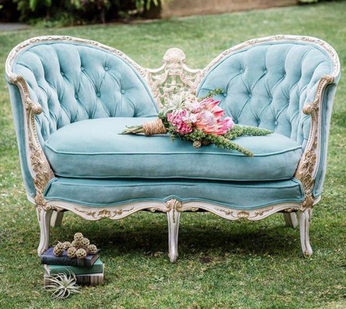 rustic flower bouquet, placed on french sofa in turquoise, with ornamental engraved cream details, placed on a lawn, near books and dried plants