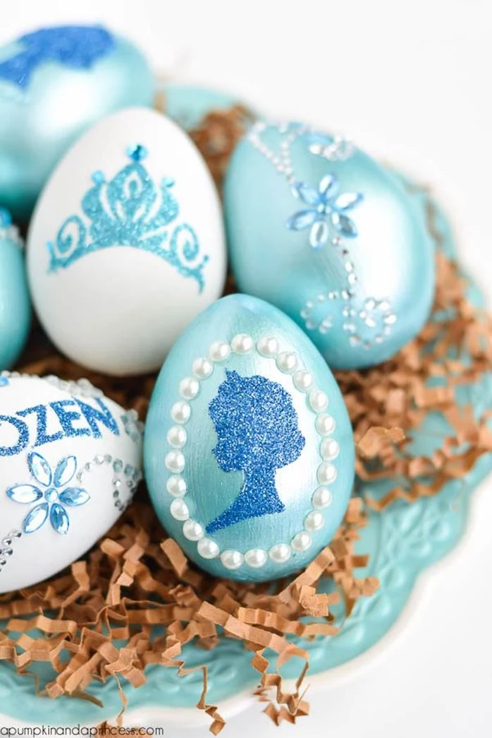 teal easter eggs, decorated with gem and pearl stickers, and blue glitter shapes, inspired by disney's frozen