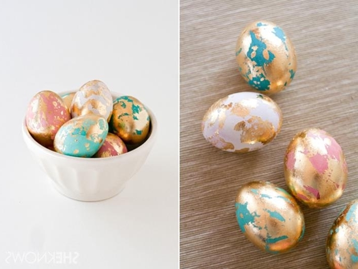 dyed eggs in pink and teal, partially covered in gold leaf, easter egg decorating, placed on beige mat, and inside a white ceramic bowl