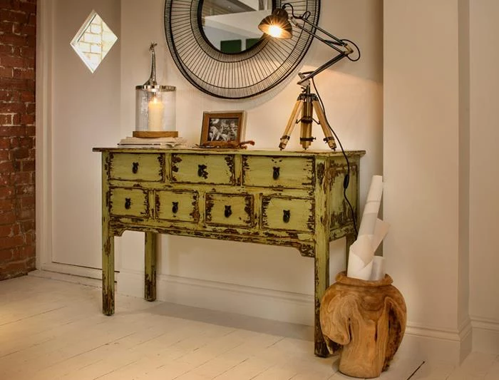 pale acid green chest of drawers, with a lamp, a framed photo and a and a candle, near round mirror, in large ornate black frame, country chic décor