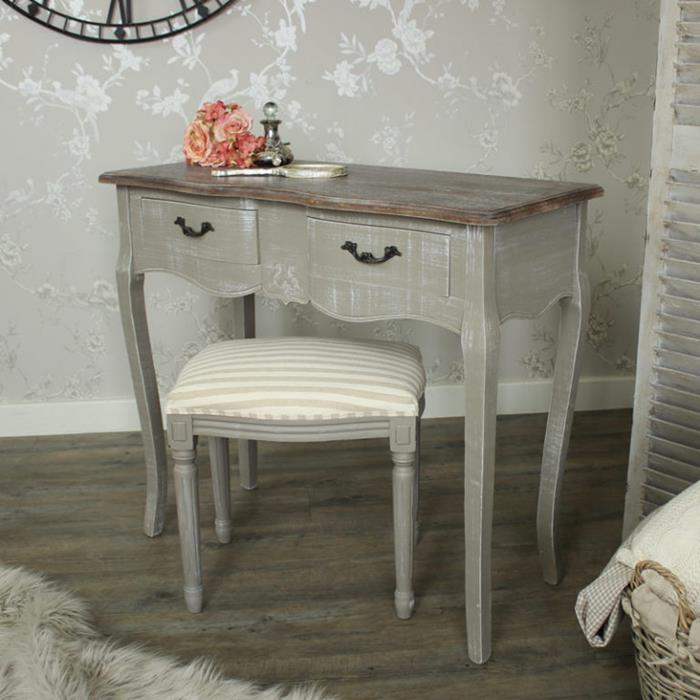desk unevenly colored in grey, with matching stool, covered in cream and beige striped fabric, country chic décor, a small bouquet of roses, magnifying glas and perfume bottle