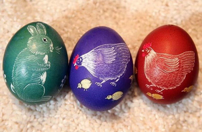 mother hens with chicks, and a bunny, drawn on three easter eggs, dyed in red, violet and green