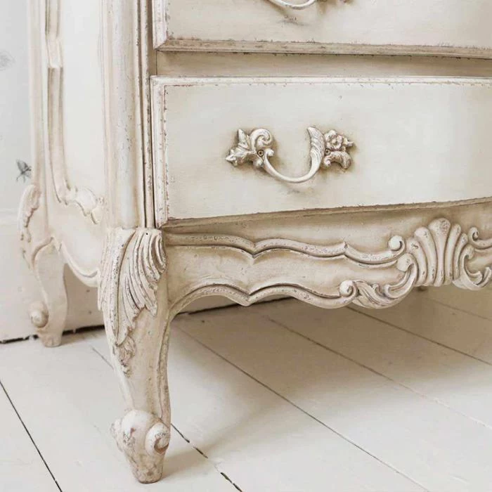 close up of ornamental details, on worn antique dresser, painted in aged cream color, country cottage furniture, white wooden floor