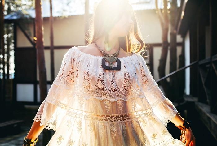 wide frilly lace, boho style tunic, in pale cream, worn with a chunky, tribal necklace and bracelets, by young brunette woman