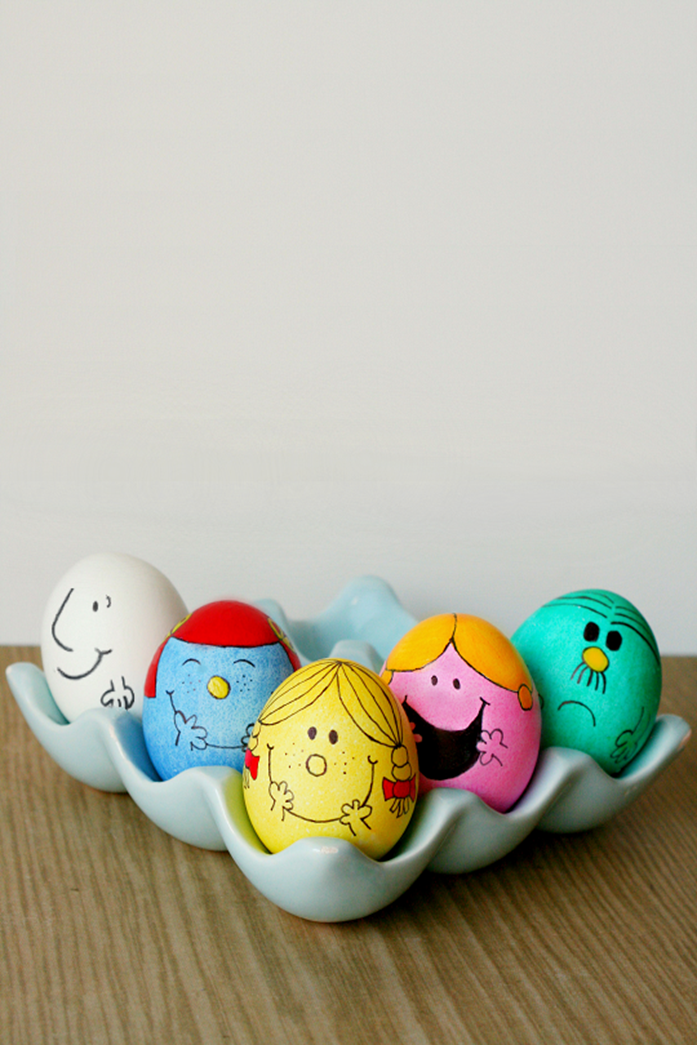 five eggs dyed in teal, pink and yellow, blue and white, made to look like characters from the little miss and mister series, easter egg ideas, inside a grey egg dish