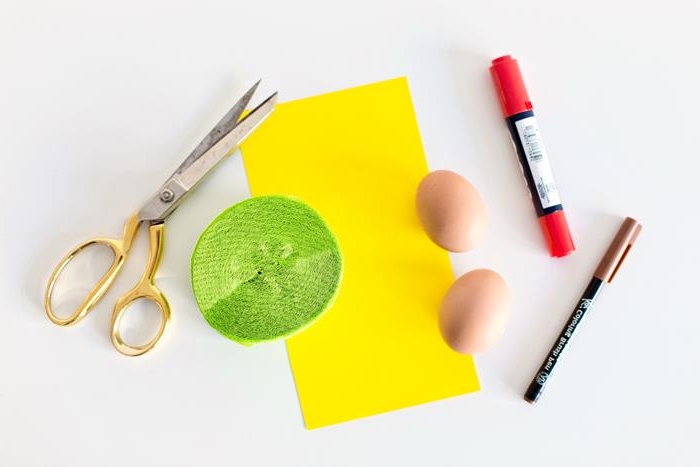 brown and red markers, dying easter eggs, a sheet of yellow paper, a roll of light green paper, a pair of scissors, two brown eggs,