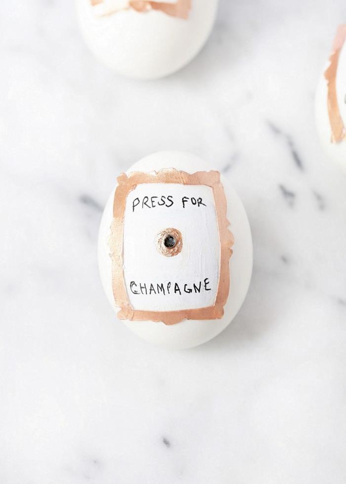 press of champagne, written in plack sharpie, near a drawing of a button, and a small frame, stuck on a white egg, easter egg decorating 