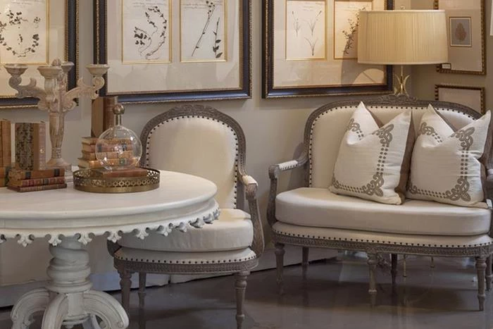 round ornamental coffee table in white, near cream and beige colored chair, and matching shabby chic sofa, with two cushions, shabby sheek decorations