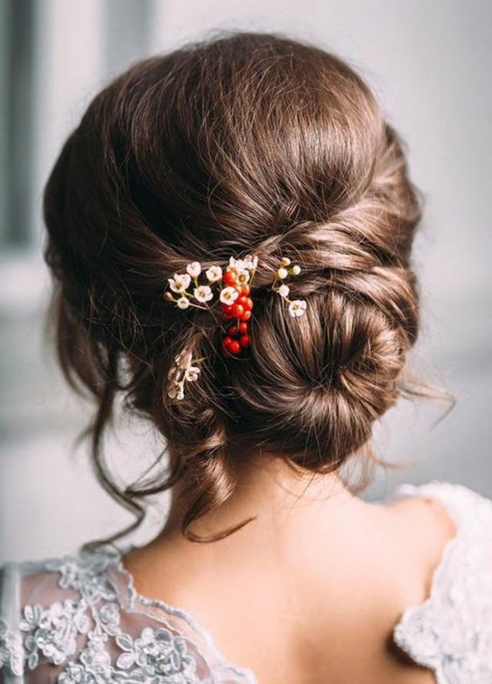 special occasion bun, with twists and curls, decorated with small red berries, and tiny white flowers, brunette hair colors, on woman wearing white lace top, with open back