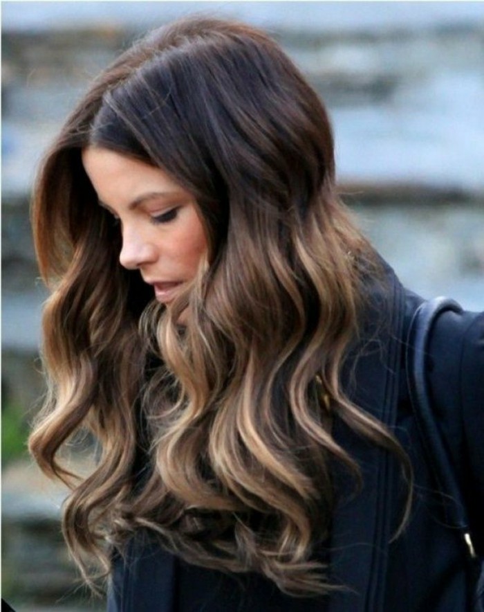 black jacket and shoulder bag, worn by woman with brown highlighted hair, with dark blonde curled strands, falling over her shoulders