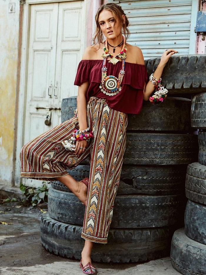 patterned wide trousers, in burgundy red and white, yellow and blue, bohemian style clothing, worn by woman in dark red frilled top, with chunky necklaces and bracelets