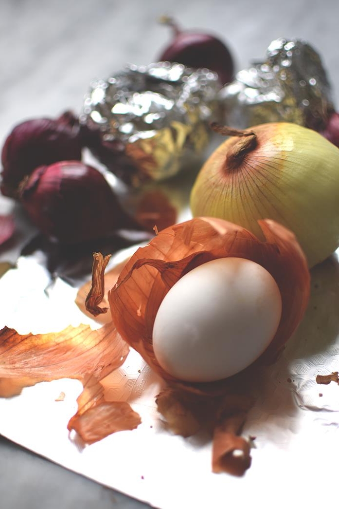 tin foil near red and yellow onions, one white egg, placed in an orange onion peel, easter egg ideas for natural egg dying