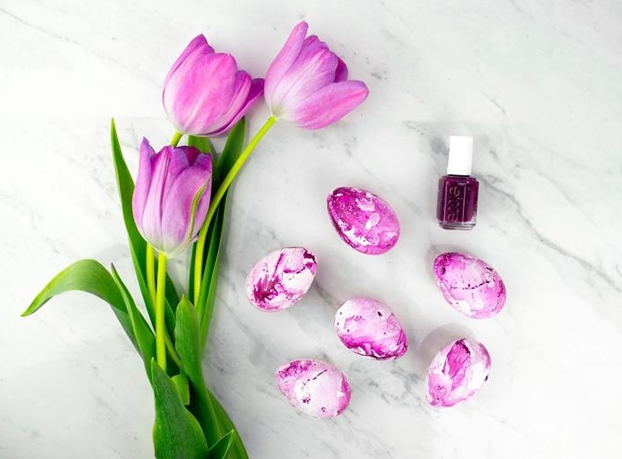tulips in pale purple, placed on a marble surface, near six white eggs, dyed in a purple marble-like pattern, a bottle of dark purple nail polish nearby