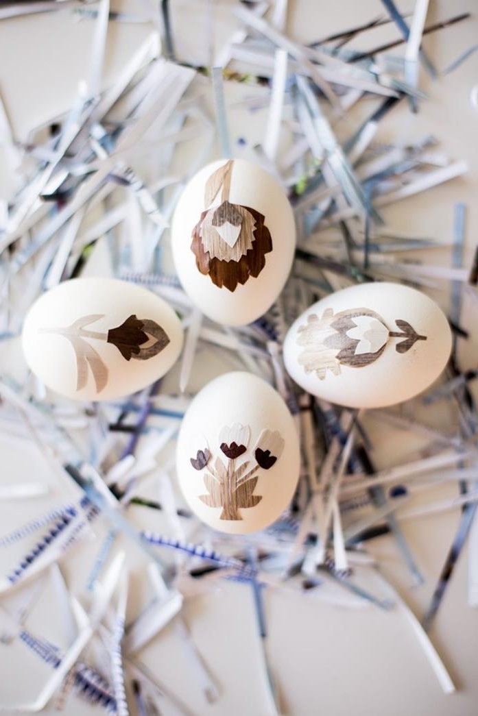 vintage inspired easter egg designs, four white eggs, decorated with grey, brown and beige paper cutouts, forming different flowers