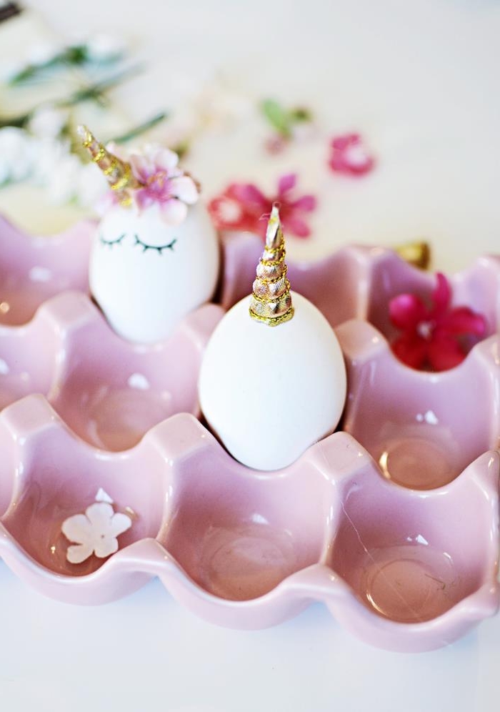 finished unicorn egg, inside a pastel pink egg dish, near a plain white egg, with a golden horn on top, dying easter eggs, tiny pink artificial flowers