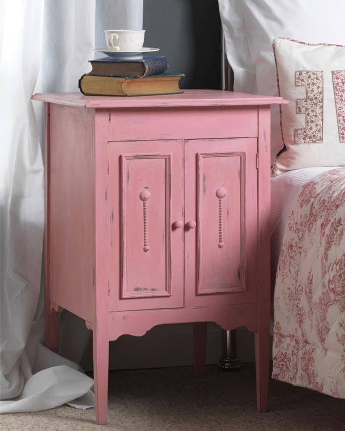 books and a teacup, on pastel pink vintage cabinet, with shabby chic look, near bed with floral covers