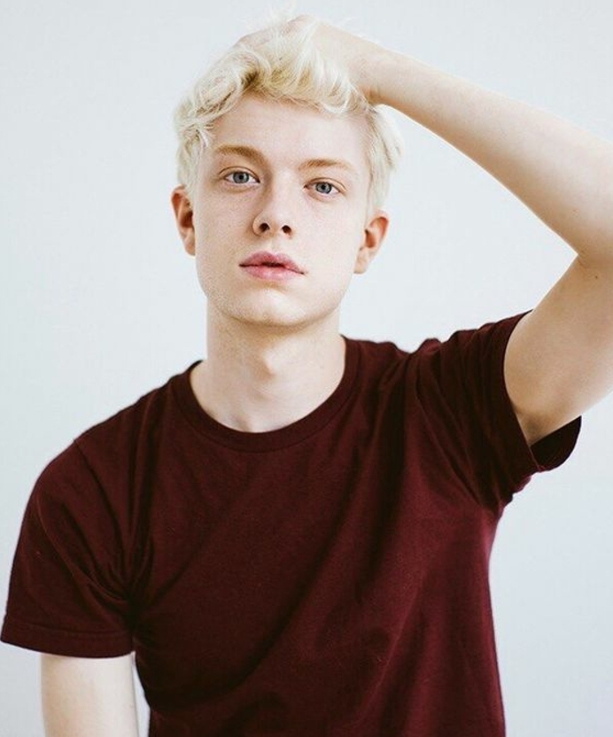 pale youth with blue eyes and short, wavy platinum blonde dyed hair, wine red t-shirt
