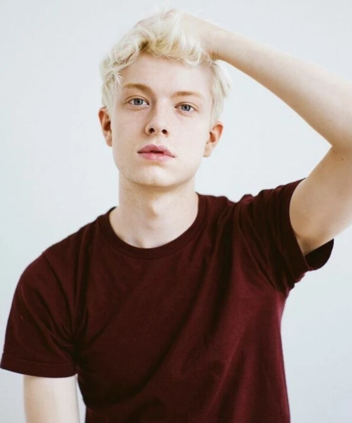 pale youth with blue eyes and short, wavy platinum blonde dyed hair, wine red t-shirt