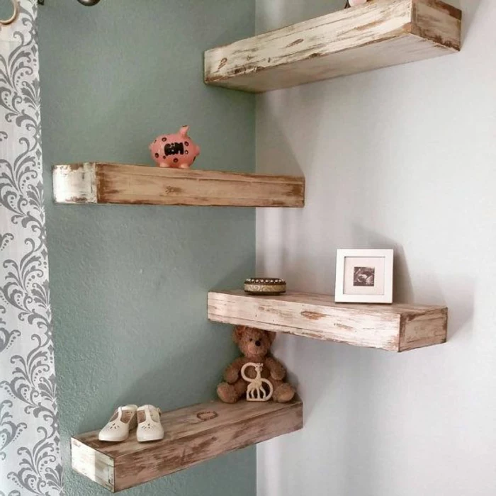 four massive wooden planks, unevenly painted in cream, mounted as shelves on grey and white walls, teddy bear and baby shoes, photo in frame and piggy bank