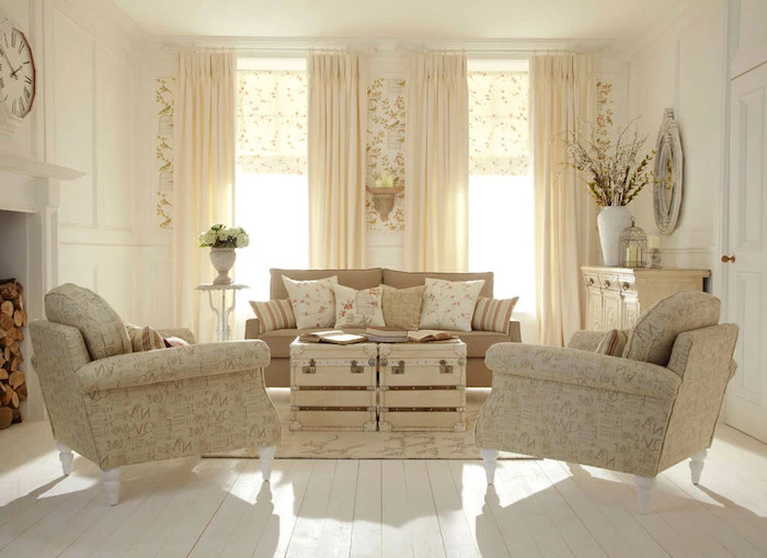 bright room with two windows, cream curtains and wooden floor, pale beige shabby chic sofa, with several cushions, patterned cream colored armchairs, coffee table made of suitcases