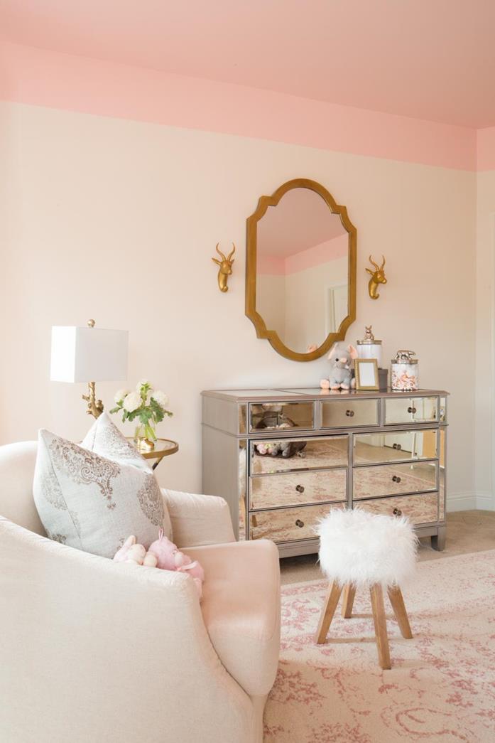 mirror covered cupboard, near cream shabby chic sofa with cushions, wooden stool with white furry top, faded vintage rug, shabby sheek pale pink walls