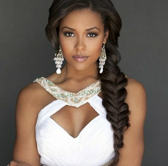 afro hair woven in a thick side braid, on woman in white evening dress, decorated with beads, wearing large white earrings, and subtle make up