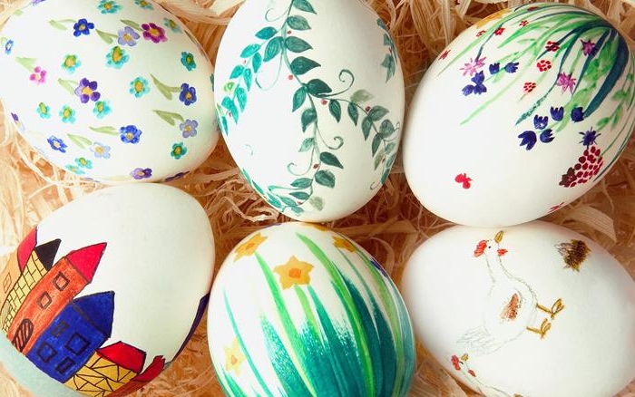 easter eggs in white, decorated with simple drawings, of different flowers, houses and birds, all done in markers