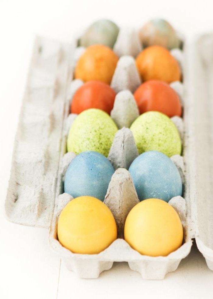 a dozen naturally colored eggs, easter egg ideas, in pale yellow, spotty blue and green, two shades of orange, and multicolored, dyed using tea