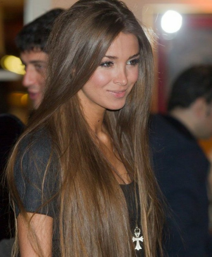soft and very long natural brown hair, parted in the middle, on smiling woman with discreet make up, wearing plain black t-shirt, and silver cross pendant