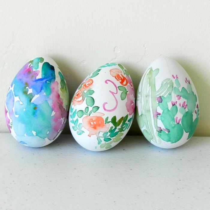 cacti and roses, painted on white eggs with watercolors, easter egg designs, letters and other shapes are also visible on the eggs