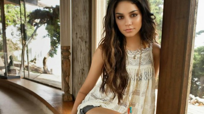 lace sleeveless top in white, and denim shorts, worn by young woman, with curled and long, brown highlighted hair 