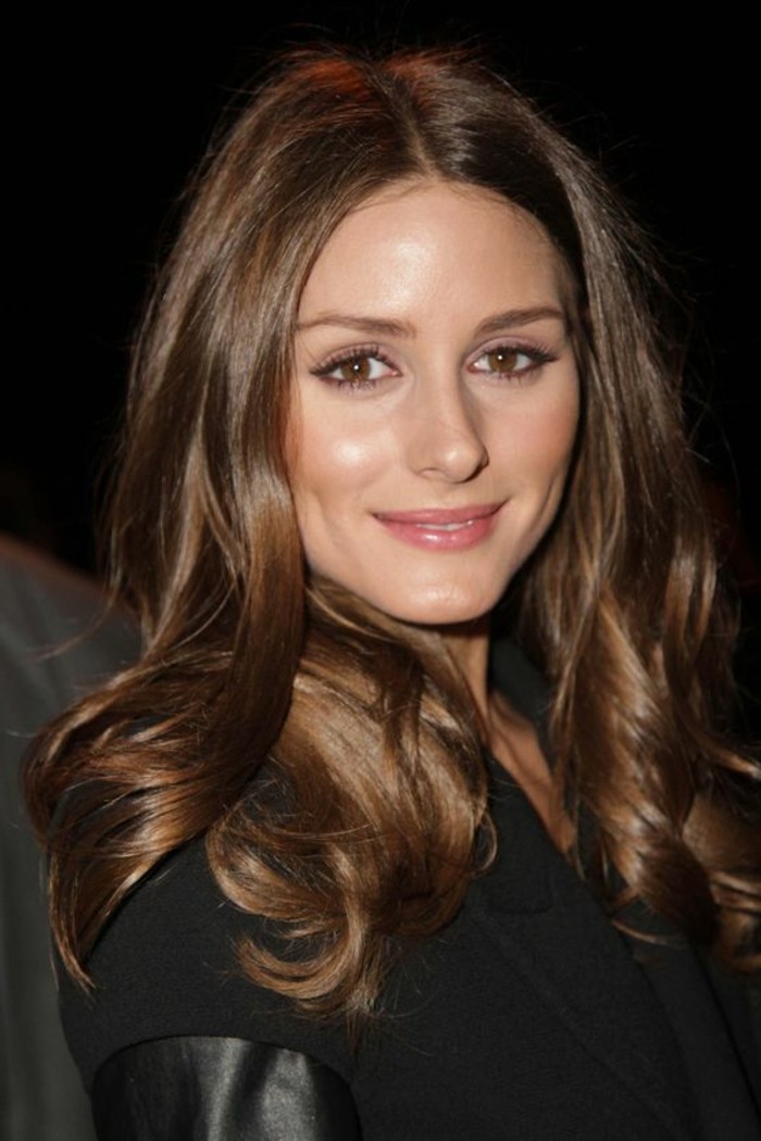 soft wavy tresses, in medium brown hair color, on smiling woman, dressed in black coat with leather trim, discreet make up and dimples