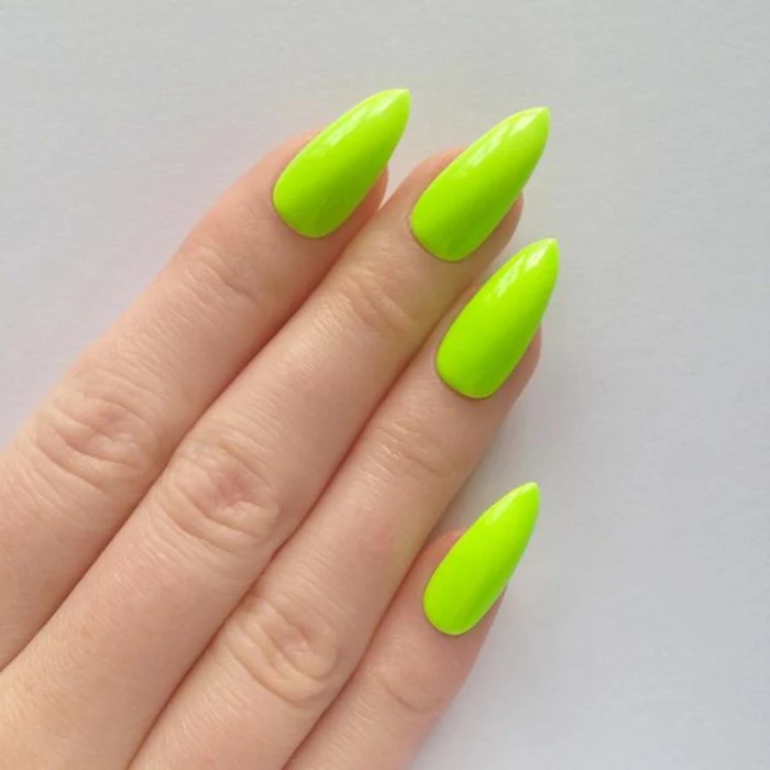 four slender fingers, with long and sharp pointy nails, painted in bright acid green, greenish-yellow color, bright and unusual