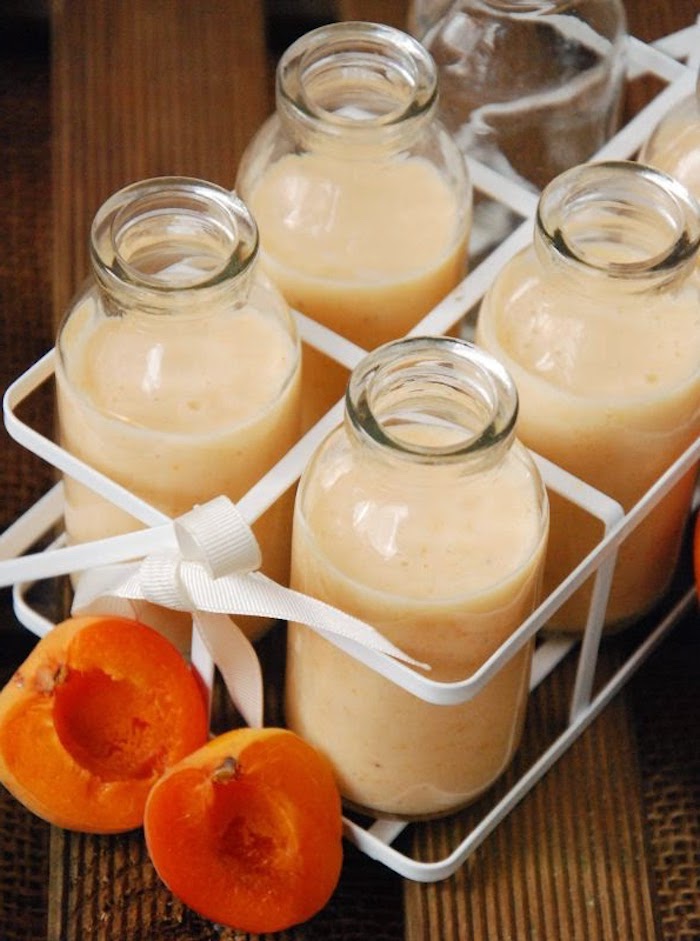 apricot slices near five bottles, filled with flavored milk, in a light orange color, fruit smoothie recipes, white bottle container with ribbon