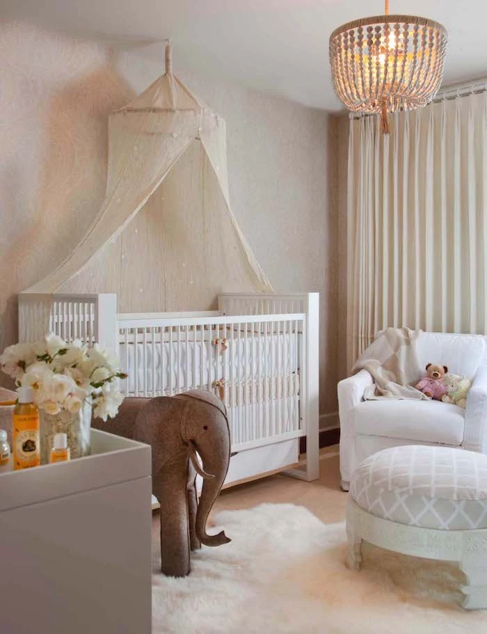 sparkly ivory baldachin, over white classical crib, near large elephant toy, made from brown fabric, girl nursery themes, white armchair nearby