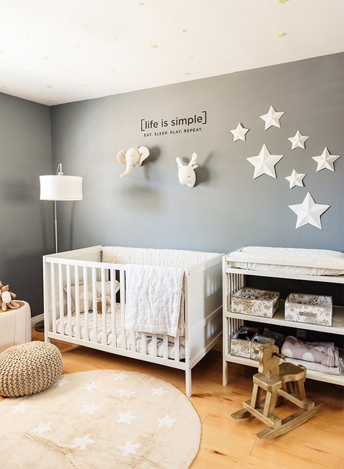 star motifs on gray wall, decorated with black text, and elephant and deer plush heads, near white baby crib, rocking horse chair, and changing table with shelves, baby girl room décor