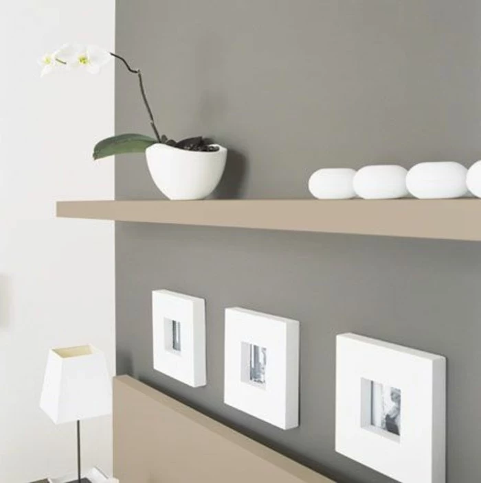 white orchid in ceramic pot, on beige shelve, with white decorations, dark grey and white walls, living room paint colors, framed photos and white lamp