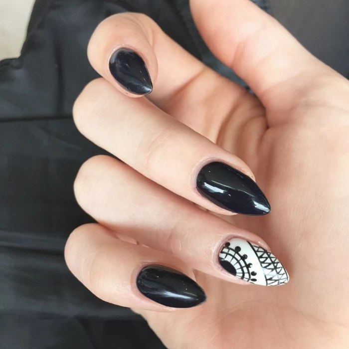 glossy and smooth, black and white nail polish, on sharp stiletto nails, with black hand-drawn decorations
